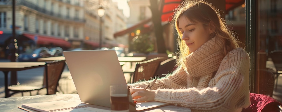 Frau macht im Café einen Französisch Einstufungstest online am Laptop